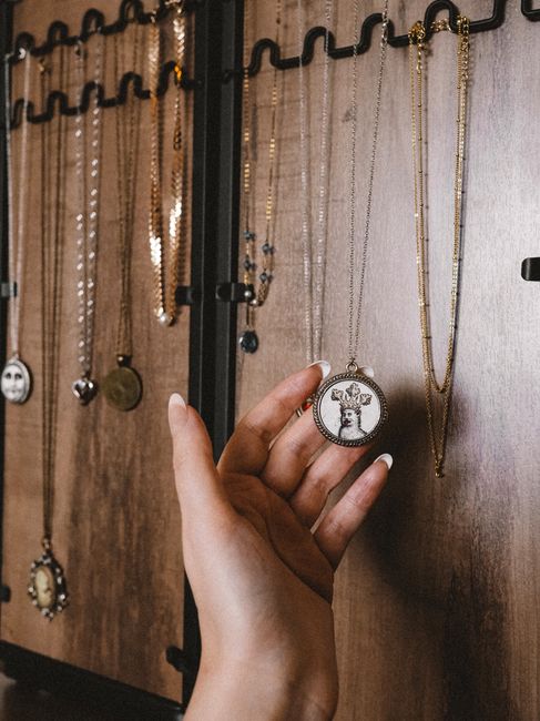 Hand selecting a necklace from a wooden jewelry display